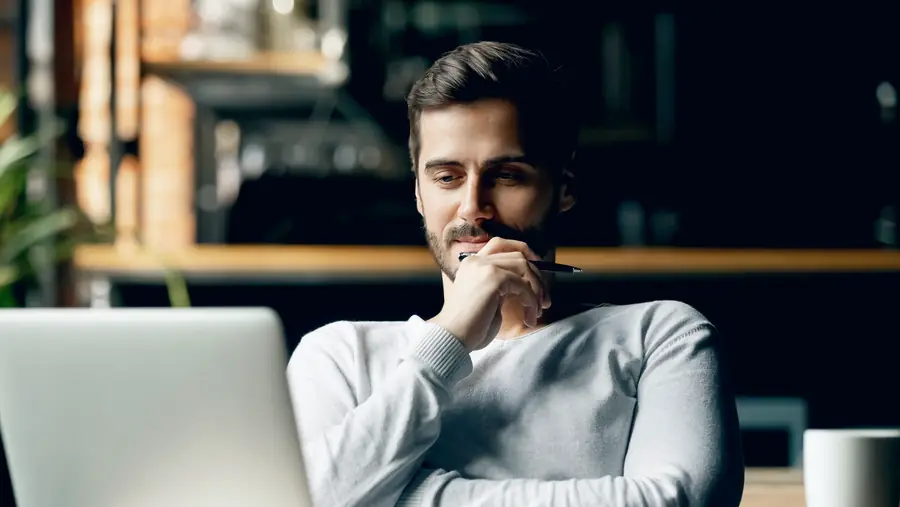 Young man sitting thoughtfully in front of his laptop